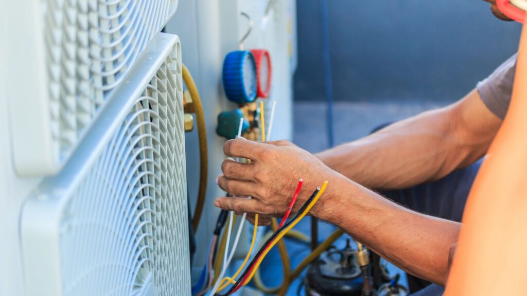 Technician installing air conditioner unit and plugging in wires